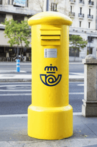Buzón amarillo de Correos con la corneta diseñada por Cruz Novillo en 1977, símbolo icónico del servicio postal español